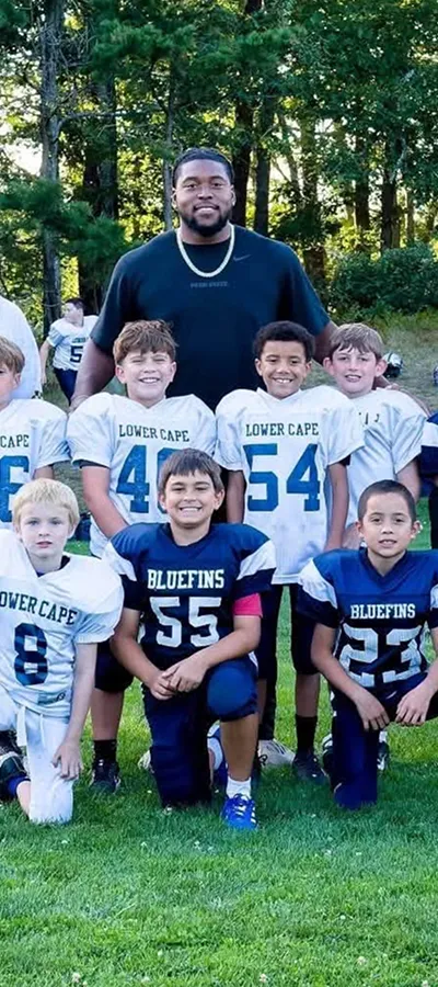 A Bluefins squad kneeling for a photo with their coach